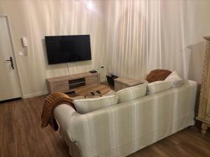 a living room with a white couch and a television at Appartement des Capucins in Cambrai