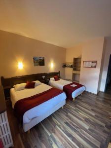 a hotel room with two beds in a room at Logis Hôtel Restaurant de la Poste in Tarascon-sur-Ariège