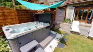 a bath tub in a yard with a blue umbrella at L'Horizon - Maison en Pierres, Vue Alpes et Nature in La Burbanche