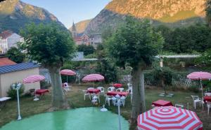 a group of tables and chairs with umbrellas in a yard at Logis Hôtel Restaurant de la Poste in Tarascon-sur-Ariège