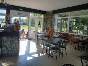 a dining room with tables and chairs in a restaurant at Camping les Marguerites in Gamaches