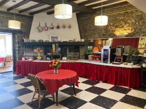 a kitchen with a table with a red table cloth at Logis Hôtel Restaurant de la Poste in Tarascon-sur-Ariège
