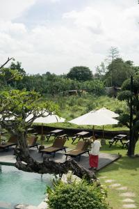 a person standing on a deck with chairs and umbrellas at Natajiwa Village, close to Canggu and Seminyak in Seminyak