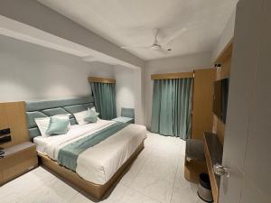 a bedroom with a large bed and a television at Hotel Pine Lake in Ahmedabad