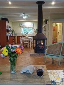 a living room with a vase of flowers and a fireplace at Uitkyk Guest House in Fouriesburg