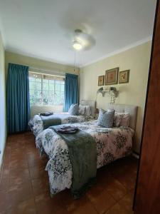three beds in a room with blue curtains at Uitkyk Guest House in Fouriesburg