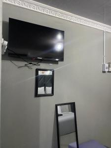 a flat screen tv hanging on a wall with a mirror at Namhla Guest House in Nongoma