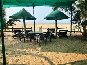 a table and chairs on the beach under umbrellas at Arabian Breeze in Tadri