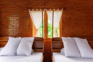 two beds with white pillows in a room with a window at Dream Hill Homestay in Cat Tien +90 photos