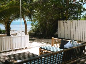 a bench sitting on the beach next to a fence at Three Palms - Beach Front Tiny House by SP Villa in Nathon Bay