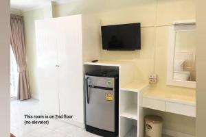 a room with a refrigerator and a tv on a wall at Thai Orchid Guest House in Jomtien Beach