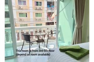 a room with a balcony with a table and chairs at Thai Orchid Guest House in Jomtien Beach