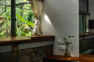 a vase sitting on a table next to a window at Malhar - Your Home Beneath The Clouds in Sultan Bathery