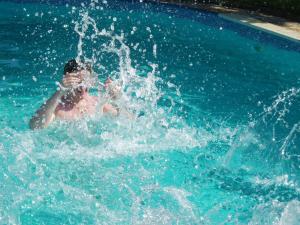 a child in a swimming pool splashing in the water at Cascina tra le vecchie vigne con piscina in Canale