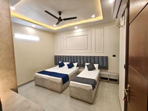 a bedroom with two beds and a ceiling fan at Pg walaah suites in Noida