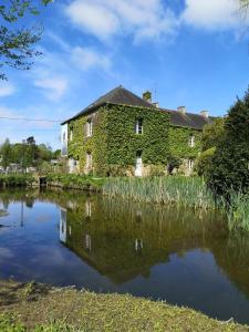 an old house covered in ivy next to a body of water at Les chambres du Lohan in Daoulas