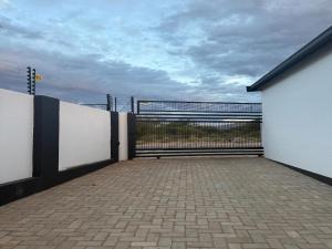 an empty parking lot with a gate and a fence at Deluxe Nest - Windhoek in Windhoek