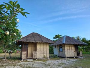 two houses with thatched roofs next to a tree at Dapearl Cottage in Baclayon