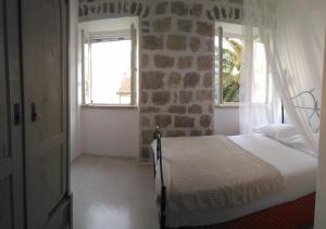 a bedroom with a bed in a room with a window at Stone House Petra in Perast