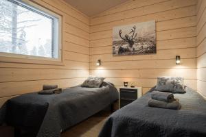 two beds in a room with wooden walls and a window at Louhi A in Äkäslompolo