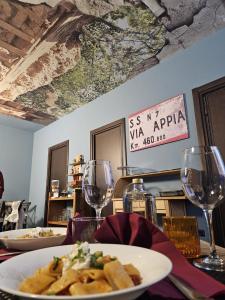a table with a plate of pasta and wine glasses at Pretoria Collection in Potenza