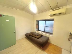 a room with a bed in a room with a window at Bridgeブリッジゲストハウス in Shimonoseki