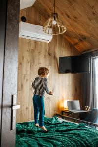 a child standing on top of a bed at Domek Jak z Obrazka in Sierpnica
