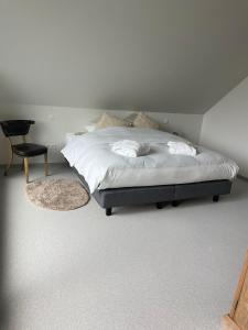 a bedroom with a bed with a chair and a chair at De Kempische Hoef in Westerlo