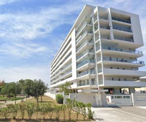 a white apartment building with trees in front of it at Brezza di Bari, Terrace & Free Parking, family and group apartment by Leviora Collection in Bari