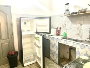 a kitchen with an open refrigerator and a sink at Guest House HEBERTOGO in Lomé +12 photos
