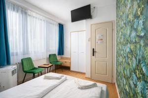 a bedroom with a bed and two green chairs at WOW City Hostel in Budapest