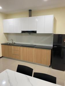 a kitchen with white cabinets and a black refrigerator at Annaz Suite Crown Pacific in Bintulu