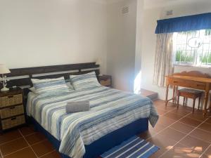 a bedroom with a bed and a desk and a window at Fishermans Cottage - BillsBest in Port Edward
