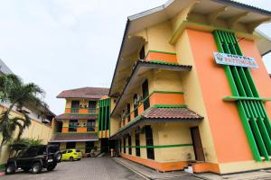 a building with green shutters on the side of it at Hotel Pattimura powered by Cocotel in Stasiun Tawang