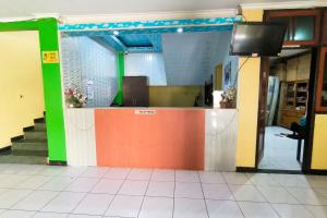 a lobby with a counter with a tv on it at Hotel Pattimura powered by Cocotel in Stasiun Tawang