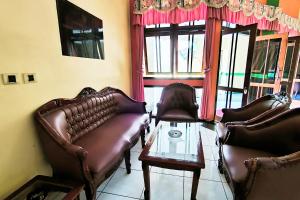 a living room with leather chairs and a glass table at Hotel Pattimura powered by Cocotel in Stasiun Tawang +29 photos