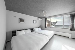 a white bedroom with a large bed and a window at Hills Niseko A in Niseko