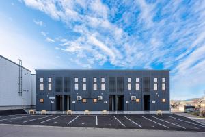 a building in a parking lot with a cloudy sky at Hills Niseko A in Niseko