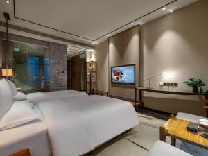 a bedroom with a large white bed and a tv at 半山酒店 in Kaili