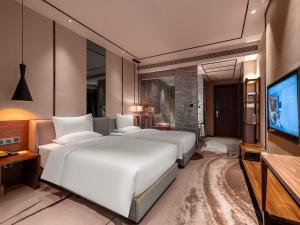 a bedroom with two beds and a flat screen tv at 半山酒店 in Kaili