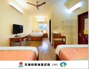 a hotel room with two beds and a television at 美村民宿 in Yuemei