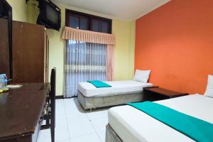 a hotel room with two beds and a television at Hotel Pattimura powered by Cocotel in Stasiun Tawang