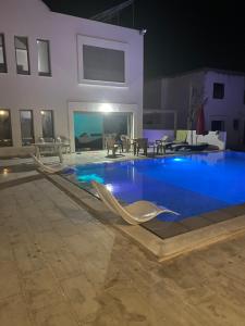 ein großes Schwimmbecken nachts mit Stühlen drumherum in der Unterkunft DarDif in Wadrān