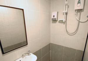 a bathroom with a shower and a sink and a mirror at Point Stay BDC Airport in Kuching