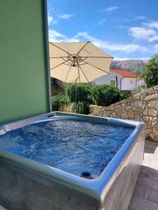 ein Whirlpool mit Sonnenschirm im Garten in der Unterkunft House Zrile with garden and jacuzzi in Baška