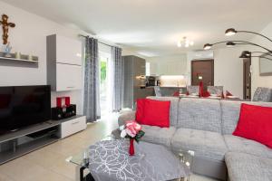 ein Wohnzimmer mit grauem Sofa und roten Kissen in der Unterkunft House Zrile with garden and jacuzzi in Baška