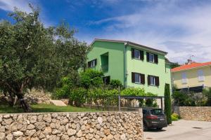 ein grünes Haus mit einem davor geparkten Auto in der Unterkunft House Zrile with garden and jacuzzi in Baška