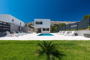 a villa with a swimming pool and lounge chairs at Villa Aurora in Baška