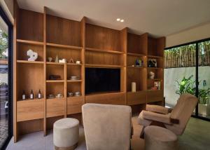 a living room with a tv and a couch and chairs at Lyvin Bingin Villas in Uluwatu