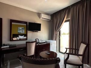 a hotel room with a desk and a table and chairs at Voyager Inn-Hotel in Palatswe